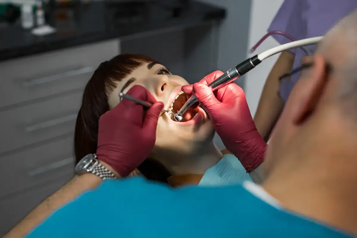 Dentist examining patient's mouth during oral cancer screening with dental instruments.